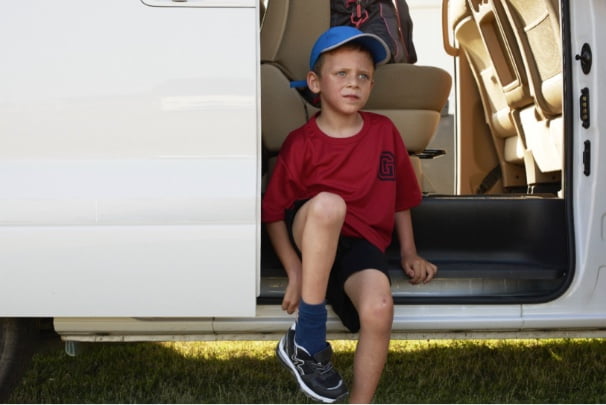 A little boy sitting in the open doorway of a van.